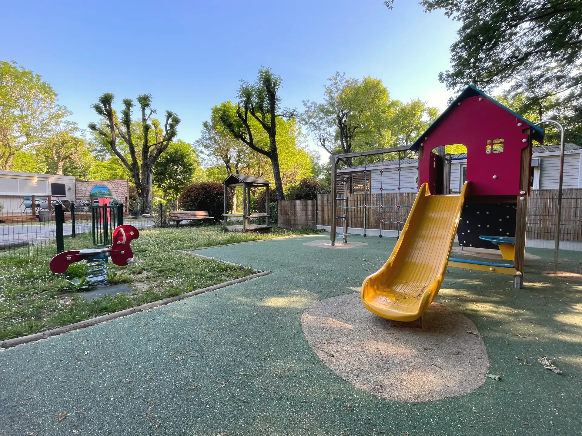 Spielplatz: eine gelbe Rutsche und ein rotes Spielhaus auf weichem Boden