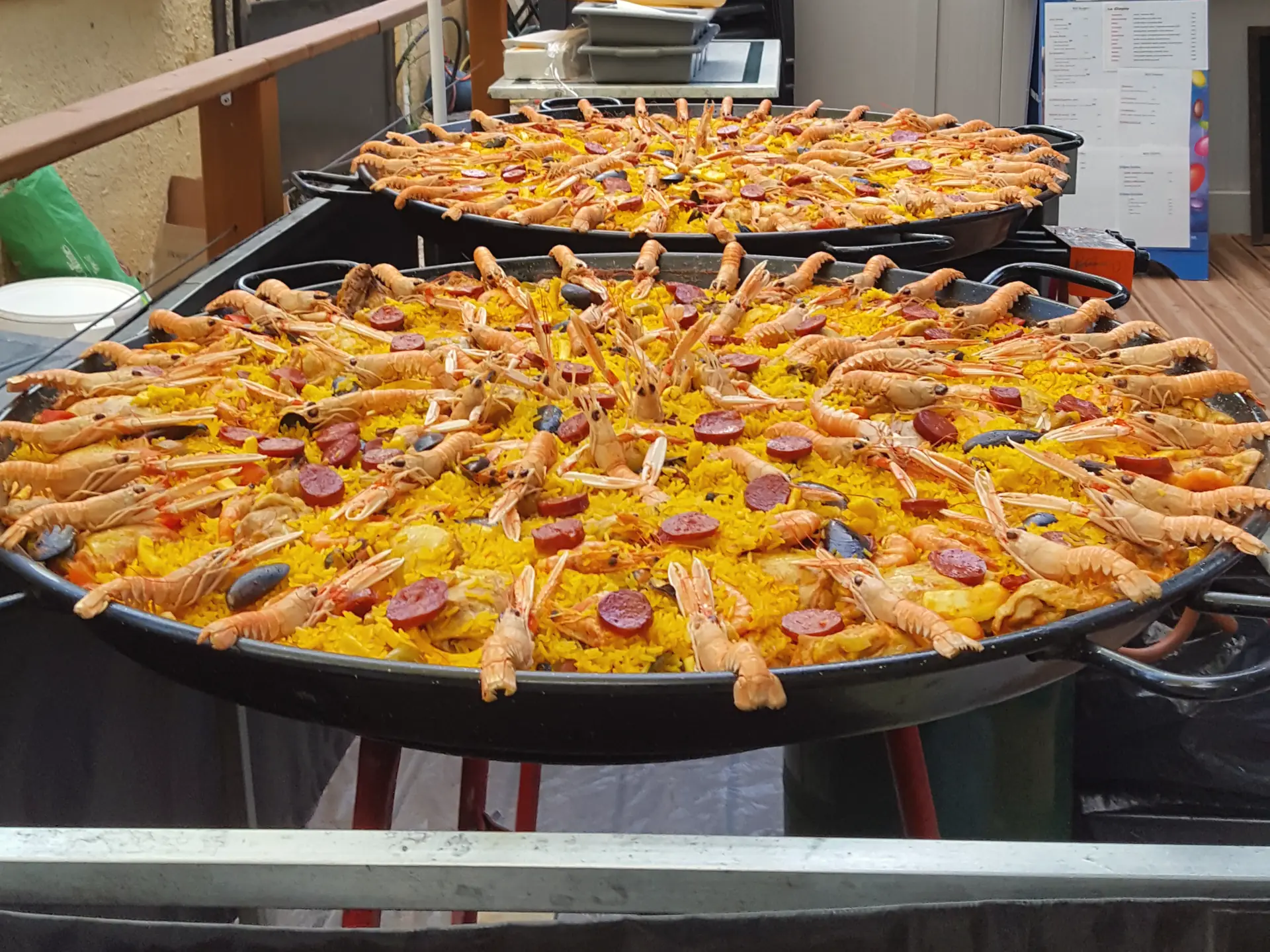 Deux grandes poêles de paella garnies de langoustines et de chorizo