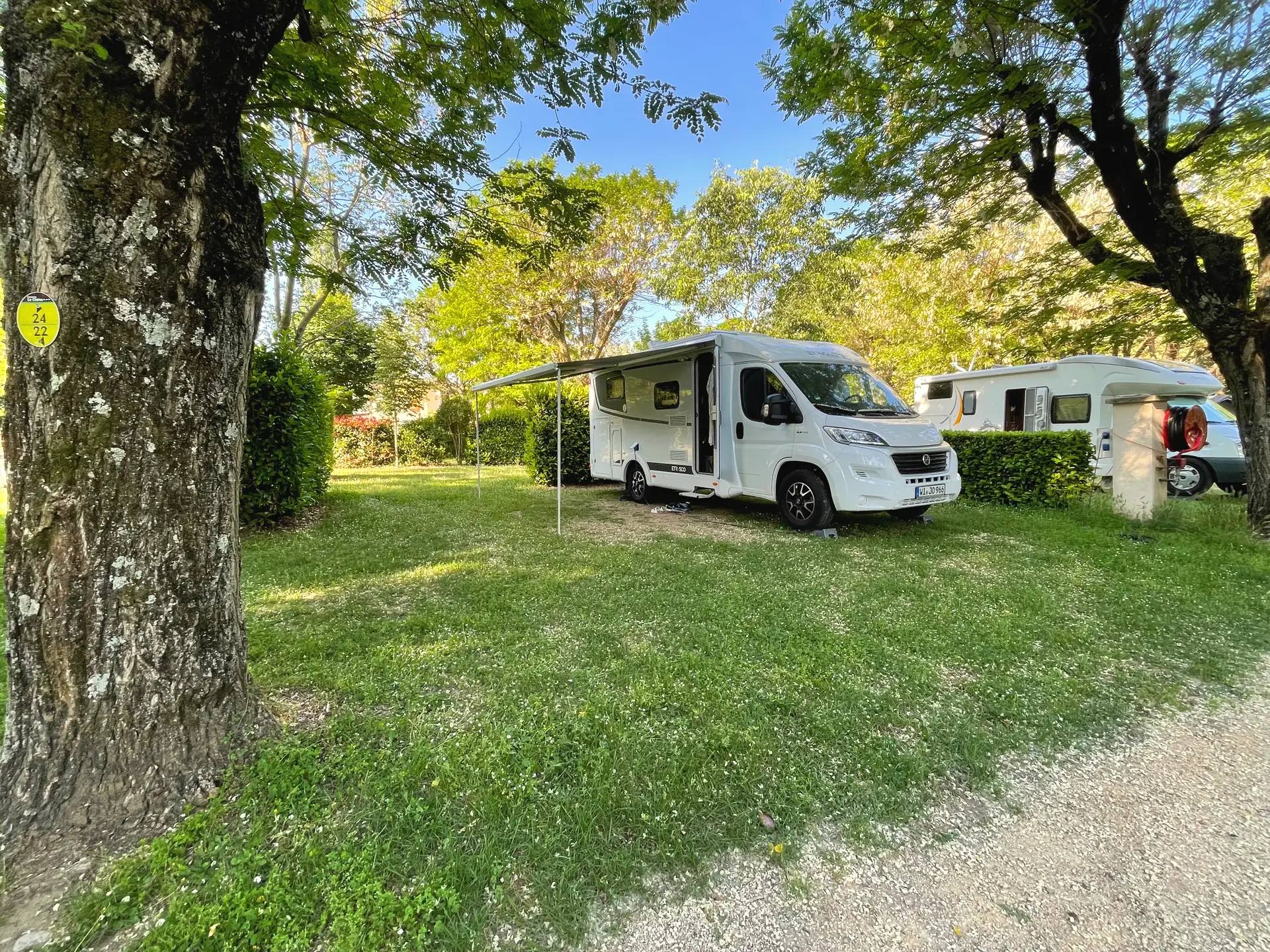 A motorhome set up on a shaded pitch
