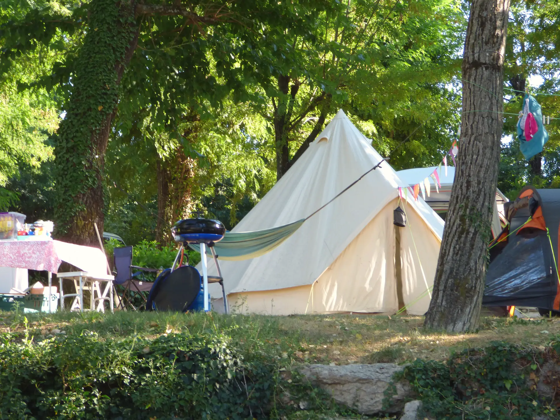 A tipi tent and its table on a pitch, under the trees
