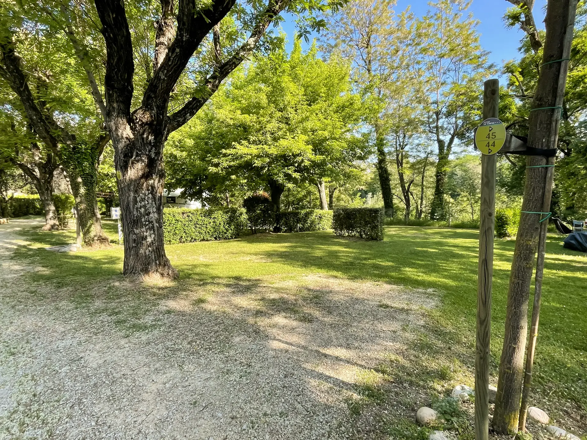 The entrance to pitches 44 and 45 and their numbered post, grass and hedges under the trees