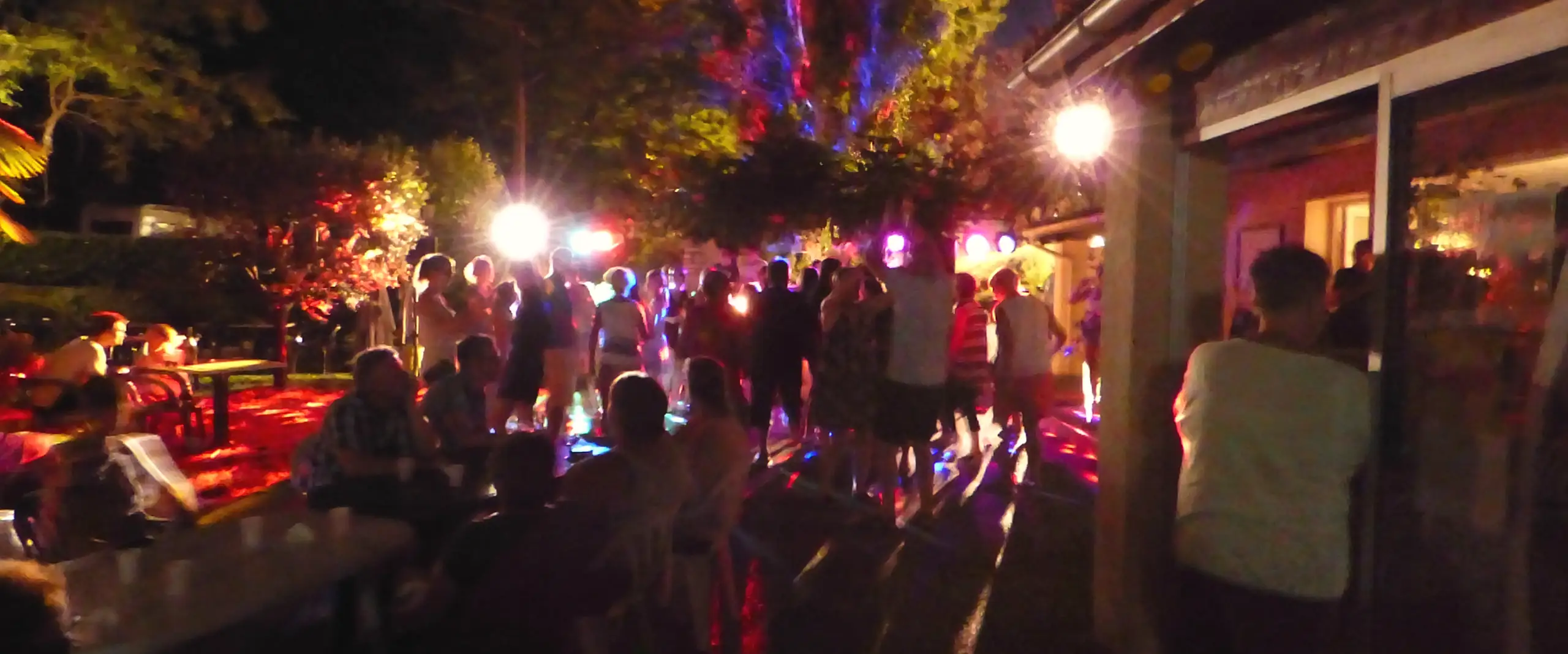 Soirée dansante sur la terrasse du camping, sous les arbres éclairés de projecteurs colorés