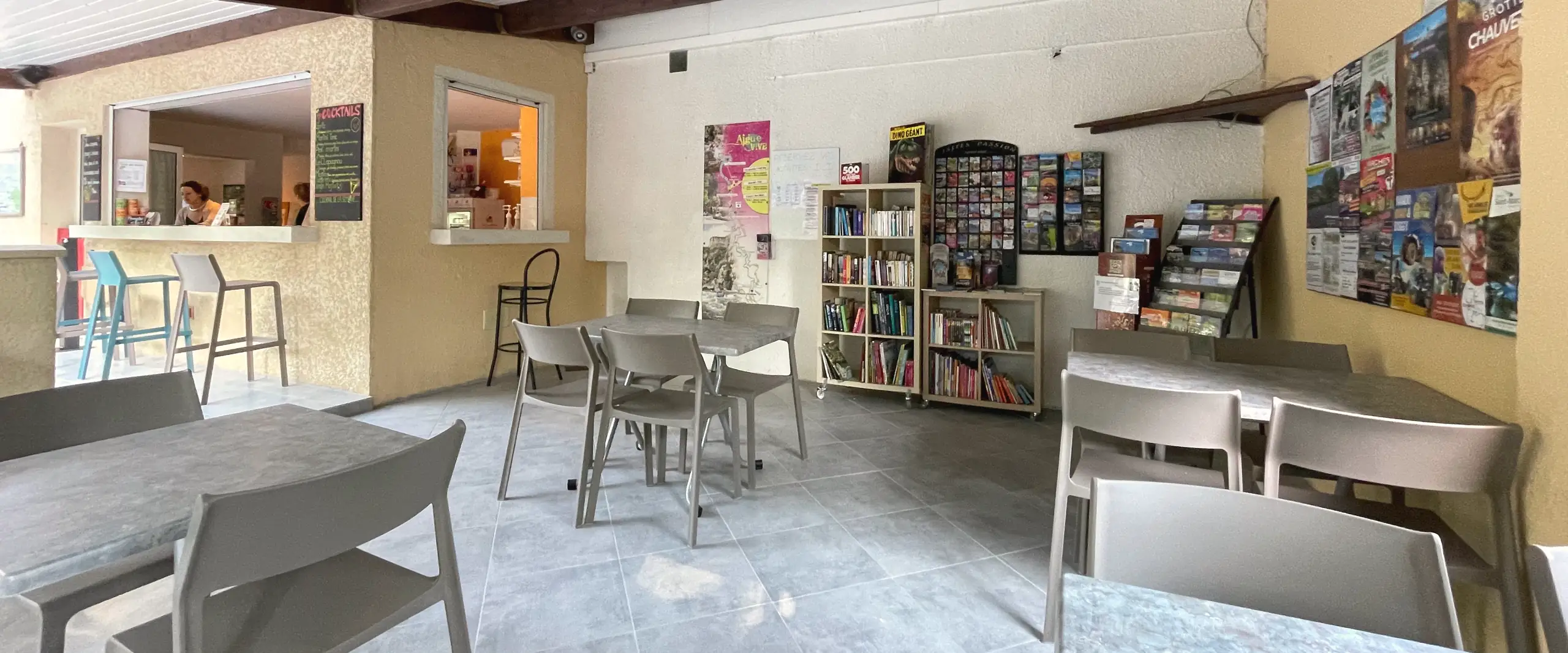 Der überdachte Bereich von Bar und Laden, mit Tischen, Theke und einer Ecke mit touristischen Informationen