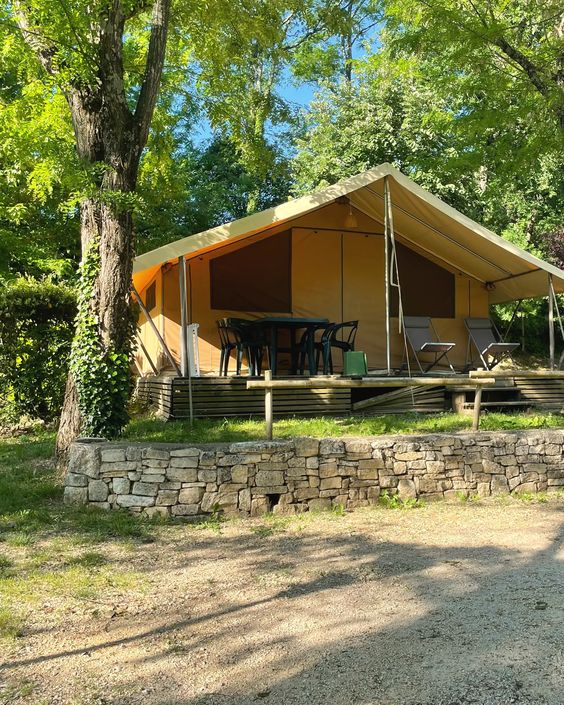 Ein Lodgezelt und seine Holzterrasse über einer kleinen Trockensteinmauer