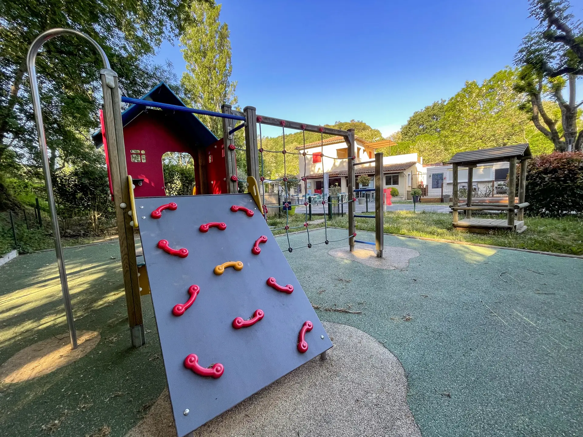The playground's climbing wall with red holds and its climbing net