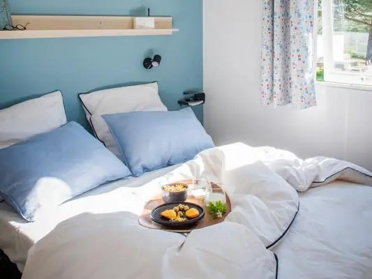 The mobile home bedroom with a 160 cm double bed and a blue headboard