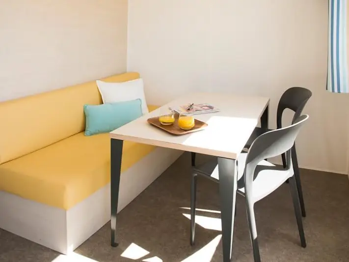 The mobile home dining area with a bench seat, table and chair by the window