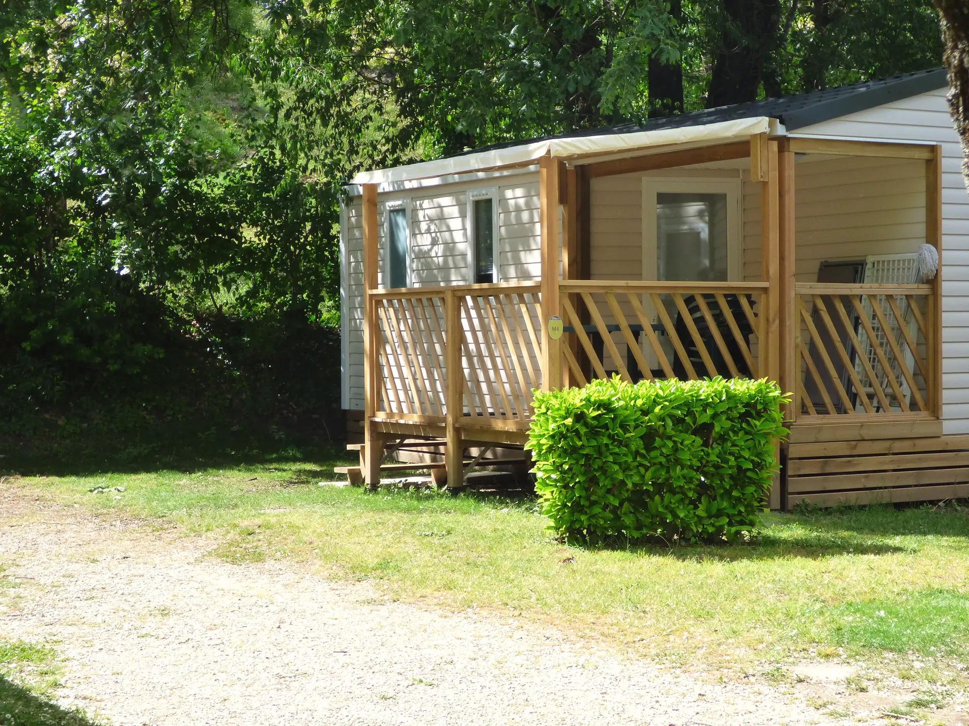 A Classic mobile home seen from the lane, with its covered wooden terrace behind a hedge