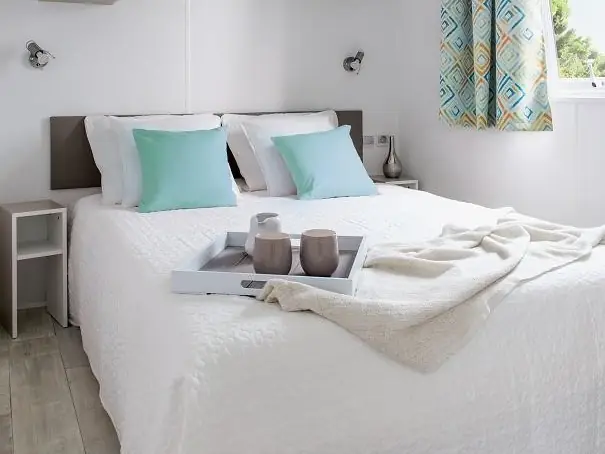 Chambre du mobil-home avec lit double et coussins