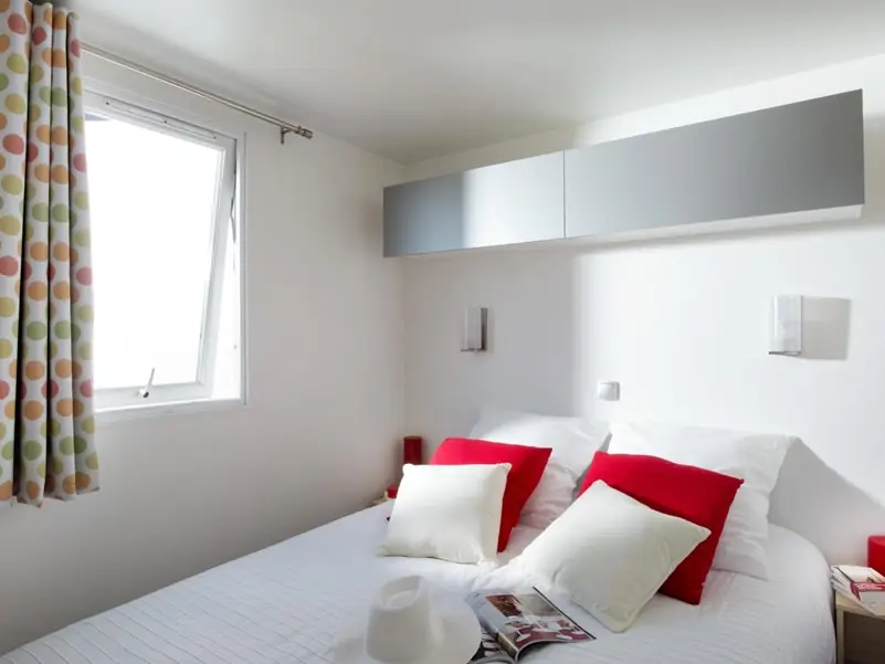 The mobile home bedroom with a double bed and red cushions
