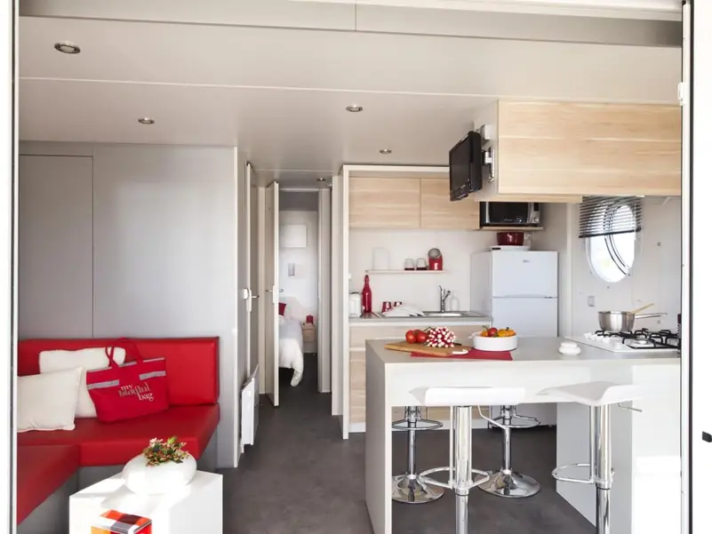 The mobile home living area with a red bench seat, equipped kitchen and counter