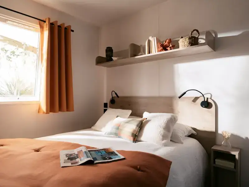 The mobile home bedroom with a double bed and an orange bedspread
