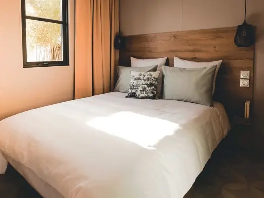Das Schlafzimmer des Mobilheims mit Doppelbett und Holzkopfteil