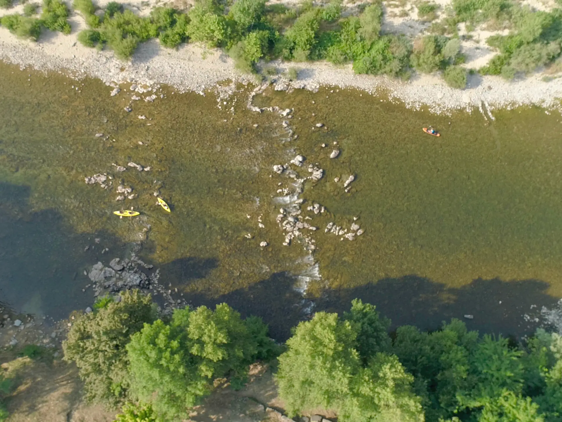 Vue aérienne de l'Ardèche avec deux canoës jaunes entre les rochers, au pied de la plage