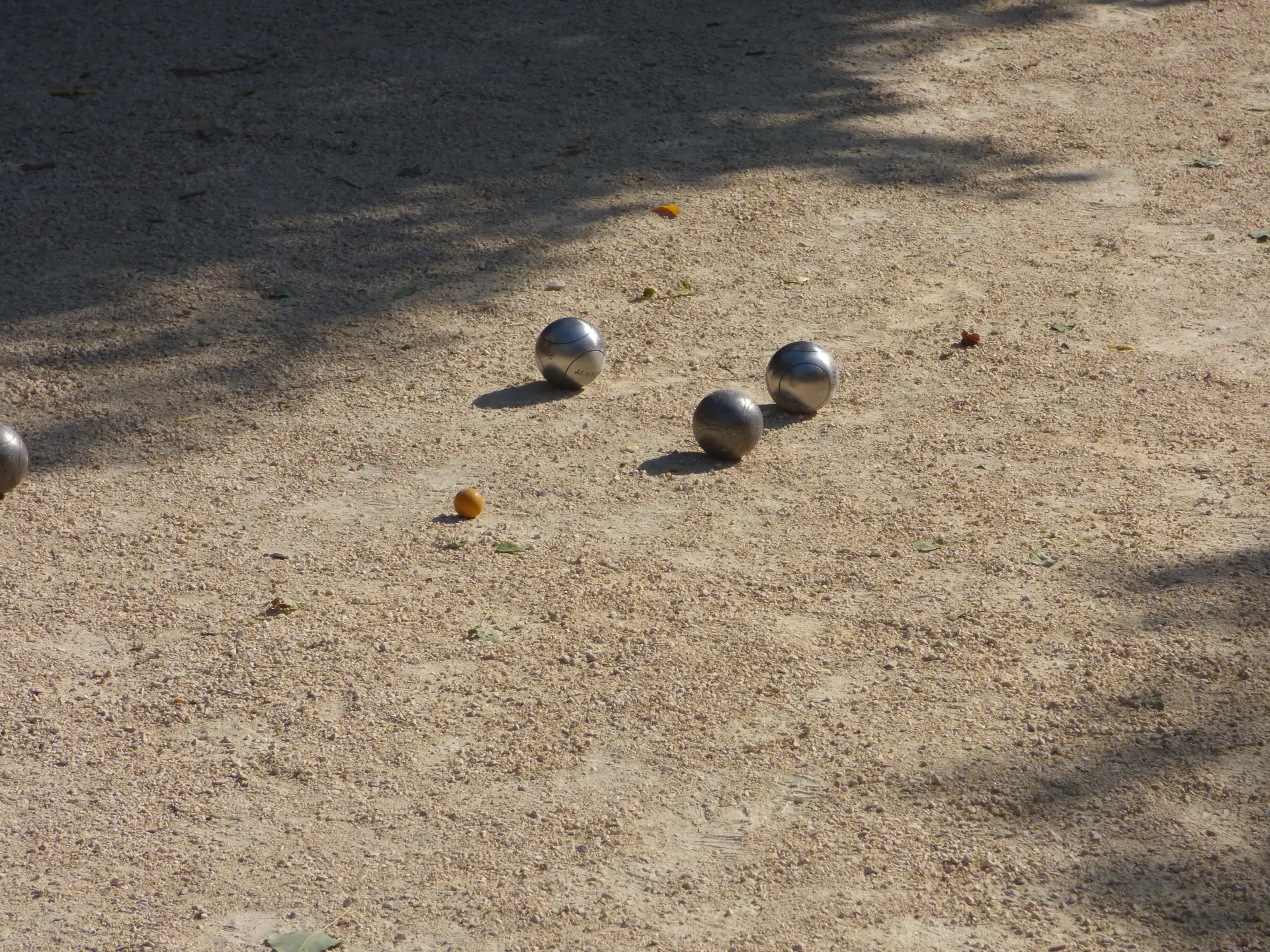 Boules de pétanque et cochonnet sur un terrain de gravier