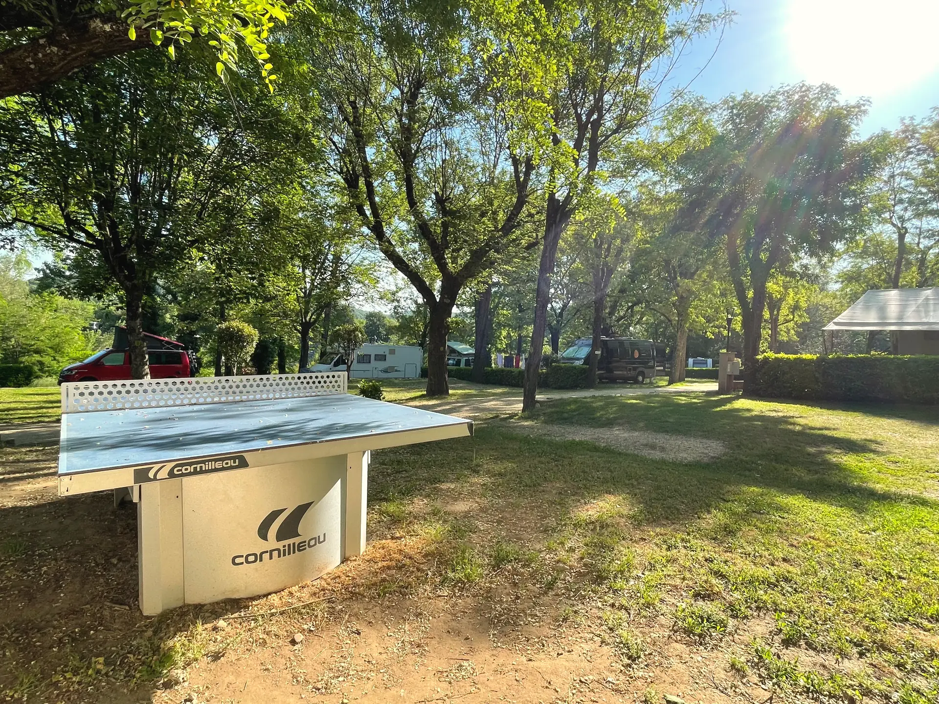 Table de ping-pong en béton à l'ombre des arbres du camping