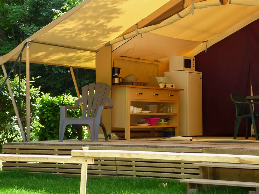Coin cuisine de la tente Lodge avec meuble en bois, réfrigérateur, micro-ondes, réchaud et cafetière
