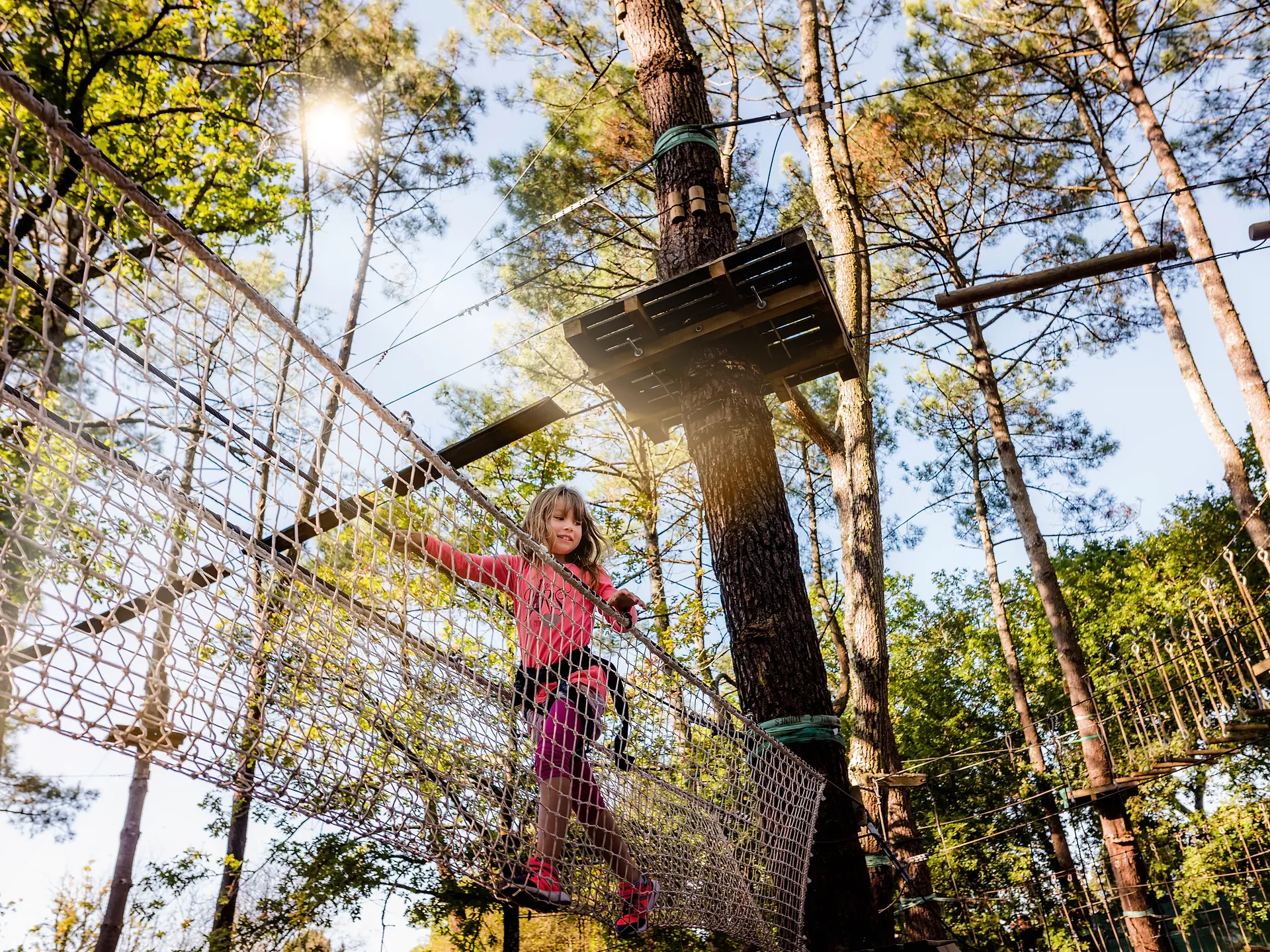 Ein Mädchen in einem Kletterwald, zwischen den Bäumen