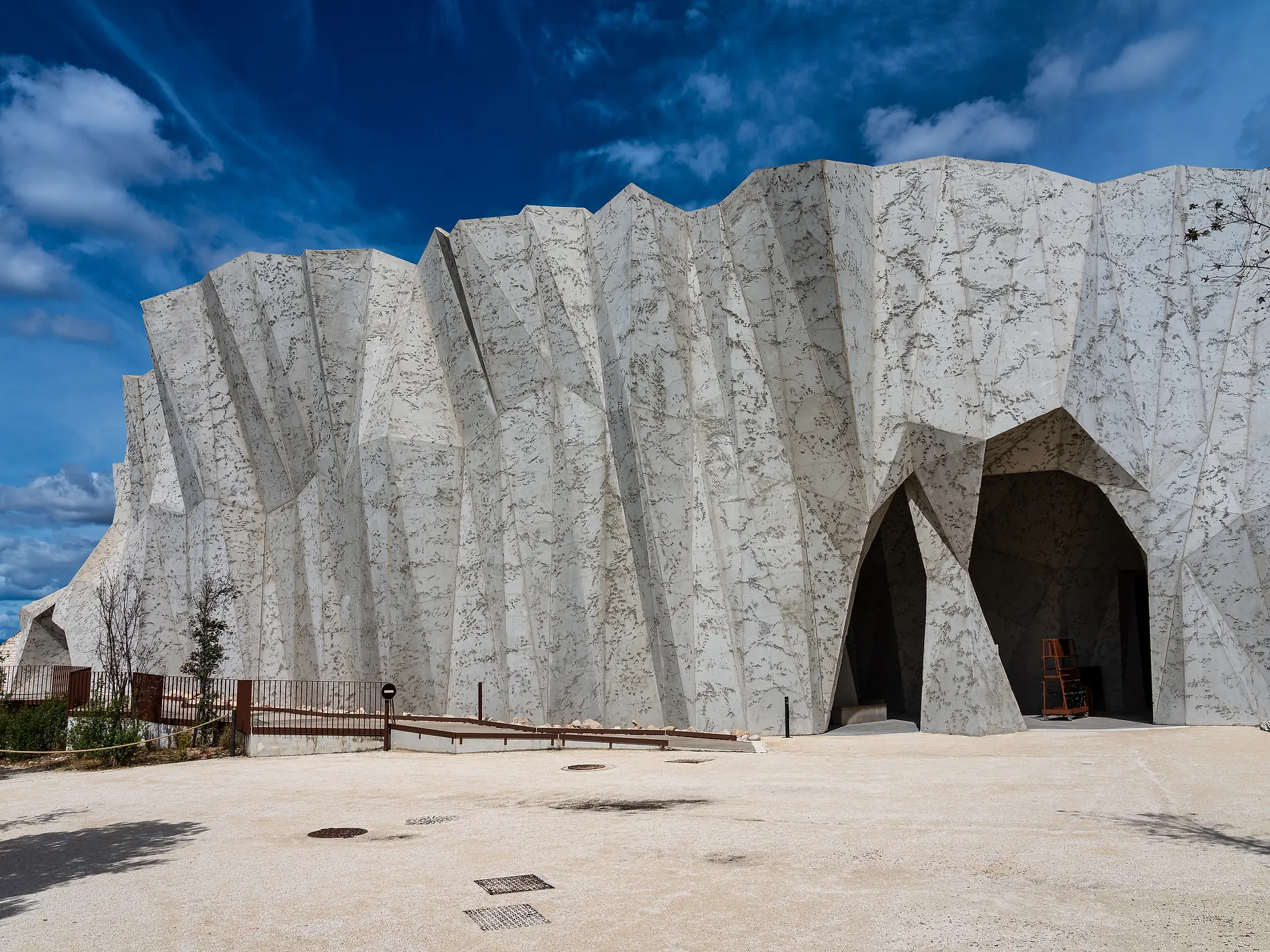 Das Gebäude der Grotte Chauvet 2 mit seinen hellen Steinmauern unter blauem Himmel