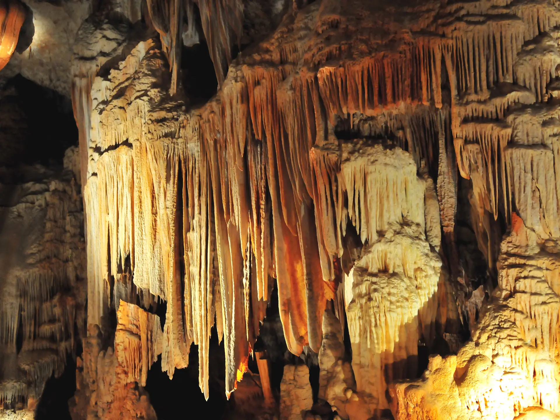 Beleuchtete Stalaktiten und Kalksinterfahnen in einer Höhle