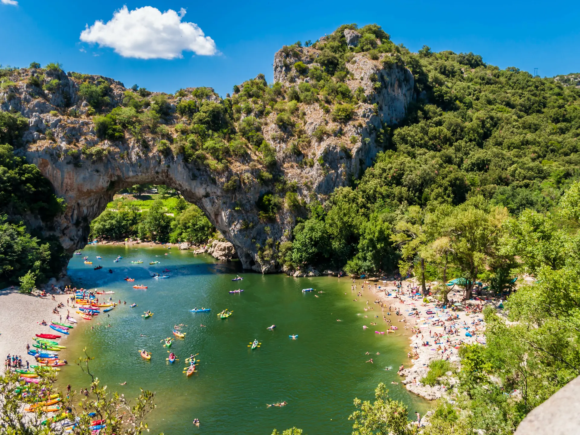 Der Felsbogen des Pont d'Arc über der Ardèche, mit Badenden und Kanus auf dem Fluss