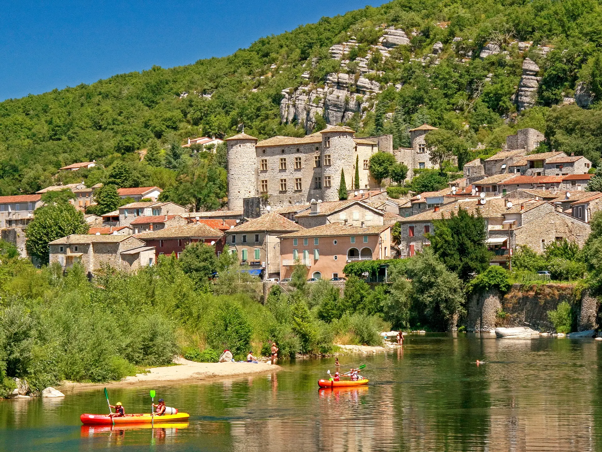 Vogüé mit seinem Schloss und seinen Steinhäusern am Ufer der Ardèche, mit Kanus
